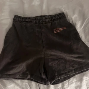 mörkgrå träningsshorts med tryck - Svarta shorts i mjuk bomull med elastisk midja och ett litet tryck framtill med texten 'new york / THE CITY WHERE DREAMS BECOME REALITY'. Perfekta för chill dagar eller träning, loose fit och bekväma att bära.