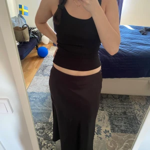 Svart långkjol från Gina Tricot - Säljer en svart långkjol från Gina Tricot i stilren och enkel design. Kjolen har en rak passform och resår i midjan för extra komfort. Materialet är lite glansigt 💗