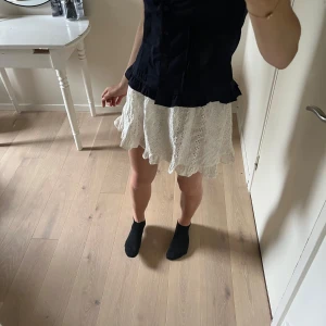 Vit kort kjol med volangkant - Supersöt vit kort kjol med broderade detaljer och volangkant längst ner. Perfekt för varma dagar och ger en romantisk vibe till outfiten. Resår i midjan för skön passform. Skriv gärna vid funderingar! Pris kan alltid diskuteras 💓