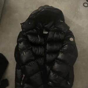 Svart Moncler dunjacka med huva - Säljer moncler jacka i modellen Maya. nfc taggen funkar samt qr koden, storlek 1. Pris går att diskutera då jag inte vet ifall den är äkta eller inte. 
