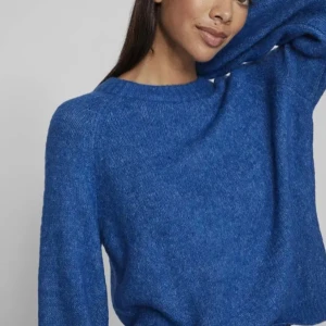 Blå stickad tröja med rund hals - Mysig blå stickad tröja med rund halsringning och långa ärmar. Perfekt för lager-på-lager och enkel att styla till jeans eller kjol. Tröjan har en klassisk passform och är superbekväm för kyligare dagar.( liten j storleken)