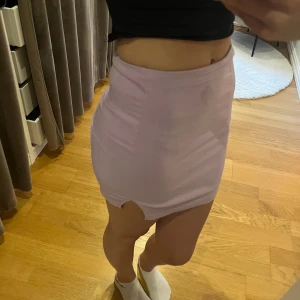 Ljuslila kort kjol med slits - Jag säljer en kort ljuslila kjol med slits som tyvärr blivit lite för liten för mig.. den är rätt kort men som ni ser på bilden så är den inte för kort. Fin liten slits på sidan för en extra detalj! Sitter bekvämt och man kan välja själv hur man vill att den ska sitta. Väldigt stretchigt material. Dragkedja i ryggen. 