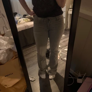 Grå bootcut jeans med fickor - Säljer ett par gråa jeans med bootcut-modell och snygga sömdetaljer. Byxorna har fram- och bakfickor samt klassisk jeansknäppning. Använda ett fåtal gånger.