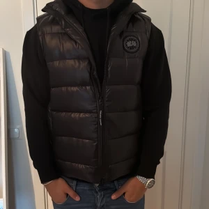 Svart dunväst från Canada goose - Säljer en svart dunväst från Canada goose med quiltad design och krage. Västen har dragkedja framtill och en diskret logga på bröstet. Perfekt att slänga över en hoodie för en clean och sportig look. Kom pm för vilka som helst funderingar och självklart är den äkta✅ finns order kvitto