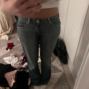 SCD Jeans bootcut med nitar - Mörkblå bootcut jeans från SCD Jeans med snygga nitar längs fickor och hällor. Bakfickorna har extra detaljer med nitar i mönster. Jeansen har låg midja och klassisk femficksmodell. Perfekta för dig som gillar lite extra bling på dina jeans. Bara att fråga om du har några frågor!!