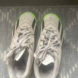 Adidas Crazyfast fotbollsskor vit/neongul - Säljer ett par Adidas Crazyfast fotbollsskor i vitt med svarta ränder och neongul sula. Skorna har snörning och är tillverkade i syntetmaterial. Perfekta för dig som vill sticka ut på planen med en riktigt snabb look. Dom är lite smutsiga men går bort med något medel tror jag