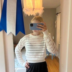 Vit stickad tröja från SAMSA Young - Säljer en vit stickad tröja från SAMSA Young. Tröjan har ett luftigt hålmönster, rund halsringning och långa ärmar. Den är croppad och har ribbade muddar vid ärmslut och nederkant. Perfekt för lager-på-lager och en chill stil.