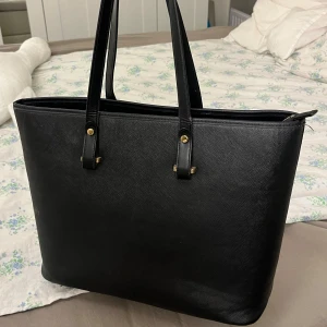 Svart stor axelväska från H&M  - Supersnygg stor axelväska från H&M med ett dragkedje fack och två småfack på insidan. Väldigt användbar och får plats med mycket som till exempel en dator!