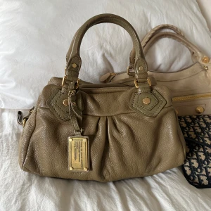 Khaki Q Classic Baby Groove väska! - Snyggaste khaki gröna handväska i bra skick från Marc by Marc Jacobs i äkta läder med gulddetaljer och dubbla handtag. Finns lite slitage i form av några repor på väskan. Välbevarad vintage modell! Perfekt för att ge en stilren touch till din outfit. Skriv privat för fler bilder. Mått 34x18x12 (undersida). Kan hämtas hemma hos mig i Nacka eller skickas men kan tyvärr inte mötas🤍