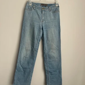 Vintage Ljusblå jeansbyxor från Rosner - Snygga ljusblå jeansbyxor från Rosner med en klassisk femficksdesign. Byxorna har en normal passform och är dekorerade med små pärlor på bakfickan för en extra touch. Perfekta för en avslappnad stil. Liten fläck på knät (se bild)