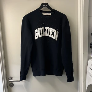 Golden Goose Tröja - En skitsnygg sweatshirt från Golden Goose i väldigt mörkblått. Riktigt cool design med lite lätt splash färg på men samtidigt inte för mycket. Även andra coola detaljer som stjärnorna bak på ryggen. Strl S.