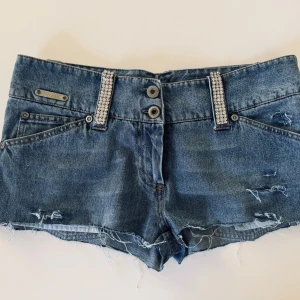 Lågmidjade jeansshorts - Säljer dessa snygga lågmidjade jeansshorts 💕Från Carla G, med diamanter / strassdetaljer både bak och fram. Passar storlek: S / 27/28 i midja 💗 Står str 42 men är ej EU storlek