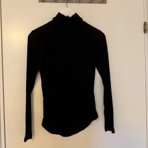 Svart polotröja ifrån primark - Säljer en stilren svart polotröja med långa ärmar. Perfekt för kyligare dagar och enkel att matcha med olika outfits. Tröjan har en klassisk design med en hög krage.