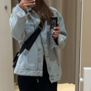Ljusblå jeansjacka - Säljer en snygg ljusblå jeansjacka med normal passform. Jackan har knappar framtill och klassiska bröstfickor. Perfekt för en avslappnad stil.