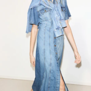 Jeansklänning med knappar - Snygg jeansklänning i blå denim med korta ärmar och knappar hela vägen ner. Klänningen har en klassisk krage och två bröstfickor med lock. Perfekt för en avslappnad stil.