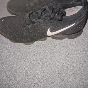 Svarta Nike Vapormax sneakers - Säljer ett par svarta Nike Vapormax sneakers med en luftig och flexibel design. Skorna har en synlig Air Max-dämpning och snörning för en säker passform. Perfekta för både träning och vardag.