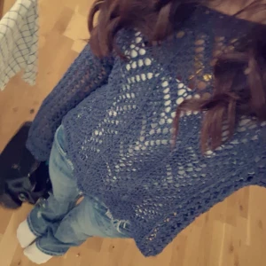 Blå stickad tröja - Säljer en blå stickad tröja med ett luftigt och öppet mönster. Tröjan har långa ärmar och en avslappnad passform, perfekt för lager-på-lager-stil. Passar bra till jeans för en casual look.