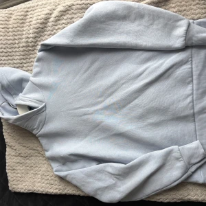 Ljusblå hoodie från Zara - Säljer en stilren ljusblå hoodie med en klassisk design. Tröjan har en bekväm passform med långa ärmar och en praktisk huva. Perfekt för en avslappnad look.