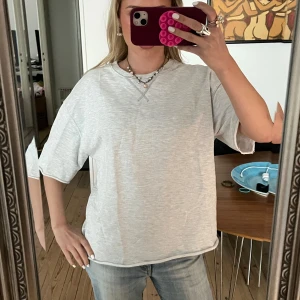 Grå t-shirt - Säljer en stilren grå t-shirt med normal passform. T-shirten har korta ärmar och är perfekt för en avslappnad look. Passar bra till jeans eller shorts.