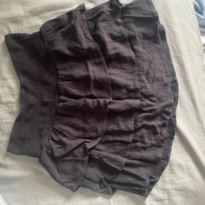 Svart volangkjol - Snygg svart kjol med volanger som ger en lekfull look. Perfekt för att styla med en enkel topp eller blus. Kjolen har en kort längd och är gjord i ett lätt material som passar bra för varmare dagar.