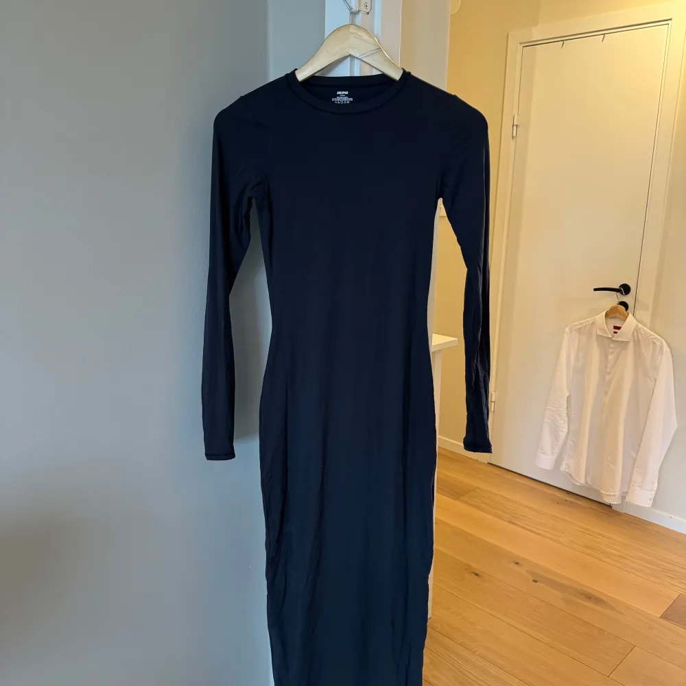 Snygg svart långklänning från Skims i en tight passform. Klänningen är tillverkad av en mjuk och stretchig blandning av polyamid och elastan, vilket ger en bekväm och smickrande silhuett. Perfekt för en stilren look. Aldrig använd, nypris 1230 kr.. Mekot.