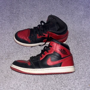 Nike Air Jordans i svart och rött - Säljer ett par klassiska Nike Air Jordans i svart och rött. Skorna har en ikonisk design med snörning och rund tå. Perfekta för sneakerheads som älskar en tidlös stil.