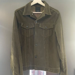 Olivgrön manchesterjacka från Sand Copenhagen - Snygg olivgrön manchesterjacka från Sand Copenhagen. Jackan har en klassisk krage och knappar framtill. Två bröstfickor med knappar ger en stilren look. Perfekt för höst och vår! Nypris 3400
