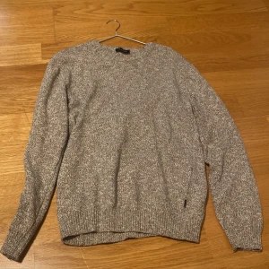 Stickad tröja från SAND Copenhagen i melerad beige – tunn & stilren - Säljer en tunn stickad tröja från SAND Copenhagen i melerad beige/grå ton. Klassisk rundhalsad modell i mjuk, lätt stretchig kvalitet som funkar året runt – perfekt som lager under kavaj eller jacka, eller bara som den är. Storlek: M Skick: Mycket fint Nypris: ca 1300kr Mitt pris: 550kr