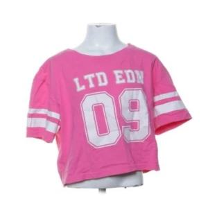 Rosa croppad t-shirt med tryck - Snygg rosa croppad t-shirt med tryck 'LTD EDM 09' i vitt. T-shirten har korta ärmar med vita ränder som ger en sportig look. Är i storlek 160