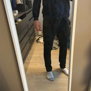 Svarta jeans från Nudie Jeans - Snygga svarta jeans från Nudie Jeans med en klassisk femficksdesign. De har en dragkedja och knapp framtill. Perfekta för en stilren look. Ny pris 1400kr men säljer de för 