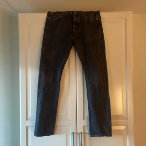 Svarta Levis 501 jeans - Säljer ett par svart/gråa Levis 501 jeans i storlek W33 L34. Passar mig bra i längd som ca 190cm. Passformen är rak med mid waist.