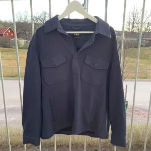 Mörkblå overshirt från Zara - Tjena! Säljer nu min snygga mörkblåa overshirt från Zara med knappar framtill och två stora bröstfickor med lock. Den är i storlek L och är i väldigt bra skick, den är bara använd ett fåtal gånger då den var lite för liten för mig. Hör gärna av dig om du har frågor eller prisförslag. Mvh Lucas