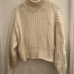 Vit stickad polotröja från H&M - Säljer en mysig vit stickad polotröja från H&M. Tröjan har en hög polokrage och långa ärmar med ribbade muddar. Perfekt för kyliga dagar!