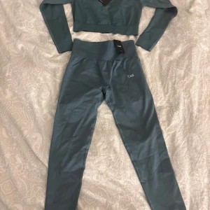 Blå träningsset från ICIW - Snyggt blått träningsset från ICIW med croppad topp och matchande tights. Toppen har långa ärmar och en tight passform, perfekt för träning. Tightsen har hög midja och ger bra stöd under aktivitet. Perfekt för gymmet eller yoga! Nypris går på 399 för tröjan och 599 för byxorna men jag säljer båda för 499kr!