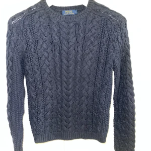 Mörkblå kabelstickad tröja från Ralph Lauren Nya!  - Säljer en snygg mörkblå kabelstickad tröja från Ralph Lauren med klassiskt flätmönster. Tröjan har långa ärmar och en rund halsringning, perfekt för kyliga dagar. Ett måste i garderoben för en stilren look. Helt nya, finns i både st M och L kommer från butiken Jackie ordpris:2499kr mitt pris:649kr. 