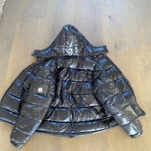 Moncler maya  - Jag kan byta mot ett annat plagg också. Snygg svart pufferjacka från Moncler utan en glansig finish, praktisk huva. Jackan har dragkedja framtill och två fickor med dragkedjor. Perfekt för kyliga dagar när du vill hålla stilen. Fungerar på våren och hösten också, 