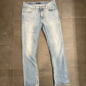 Ljusblå jeans från Nudie Jeans - Säljer ett par ljusblå jeans från Nudie Jeans med en klassisk femficksdesign. De har en rak passform och är tillverkade i denim med en lätt tvättad look. Perfekta för en avslappnad stil.