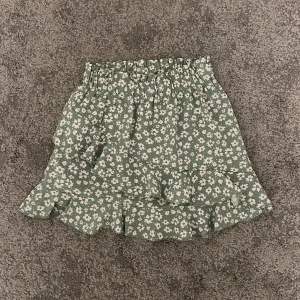 Volangkjol - Kort, grön volangkjol med blommigt mönster. Den är från SHEIN. Det är storlek S men är ganska kort som en XS/XXS. 