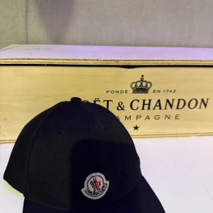 Svart keps från Moncler - Snygg svart keps från Moncler med en broderad logotyp framtill. Perfekt för en stilren look oavsett tillfälle.