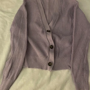 Ljuslila stickad kofta från 157 - Säljer en ljuslila stickad kofta från 157 med knappar framtill. Koftan har en v-ringad design och långa ärmar. Perfekt för att hålla sig varm och stilren. Passar bra till både jeans och kjol. 🌸