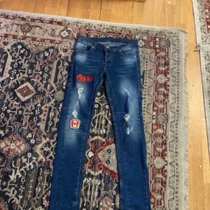 Blå jeans med broderade detaljer från Dsquared2 - Snygga blå jeans från Dsquared2 med broderade detaljer och slitningar. De har en straight passform och är dekorerade med coola patches. Perfekta för en trendig look.
