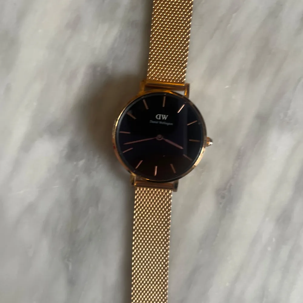 Petite Pressed Melrose klocka från Daniel Wellington. Klockan är tillverkad i polerat rostfritt stål och har en plätering i roséguld. Svart urtavla. 24 mm. . Asusteet.