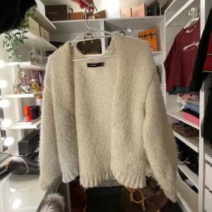 Vit stickad kofta från vero moda - Mysig vit stickad kofta från Vero moda med en avslappnad passform. Perfekt för kyliga dagar, med långa ärmar och en öppen design framtill. Enkelt att matcha med olika outfits för en stilren look.