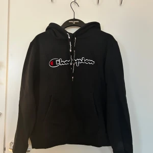 Svart hoodie från Champion - Säljer en svart hoodie från Champion med deras ikoniska logga på bröstet. Tröjan har en justerbar luva med snören. Skriv gärna om ni har några frågor! 💗