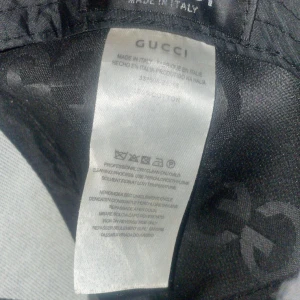 Svart keps från Gucci - Snygg svart keps från Gucci med det ikoniska GG-mönstret. Kepsen har en justerbar rem baktill för perfekt passform. Tillverkad i Italien, vilket garanterar hög kvalitet och stil.