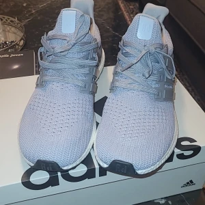 Grå Adidas Ultraboost 1.0 sneakers - Snygga grå Adidas Ultraboost sneakers med stickad ovandel och klassisk snörning. Perfekta för både träning och vardag. De har en bekväm och responsiv Boost-sula som ger extra komfort. Box ingår