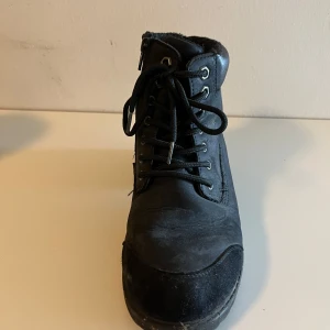 Svarta boots med snörning och dragkedja - Snygga svarta boots med både snörning och dragkedja för enkel på- och avtagning. De har en robust sula och är perfekta för kyligare väder. Skorna har en klassisk design som passar till många olika stilar.