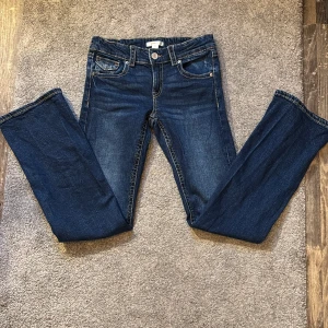 Mörkblå bootcut jeans från Gina tricot - Snygga mörkblå jeans från Gina Tricot med klassisk femficksdesign och knappgylf. Jeansen har en rak passform och är perfekta för en avslappnad stil. De är tillverkade i ett slitstarkt denimtyg som ger en tidlös look.