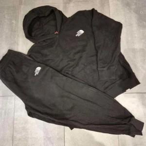 Svart hoodie från The North Face - Säljer en svart hoodie från The North Face med klassisk logga på bröstet. Tröjan har en bekväm passform med långa ärmar och en praktisk huva. Perfekt för kyliga dagar eller avslappnade stunder. Hör av dig vid intresse!