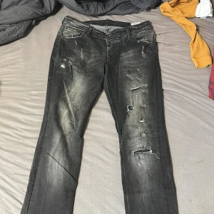 Svarta jeans från Dsquared2 - Snygga svarta jeans från Dsquared2 med slitna detaljer och en cool tvättad look. De har en klassisk femficksdesign och knappgylf. Perfekta för en trendig och avslappnad stil.